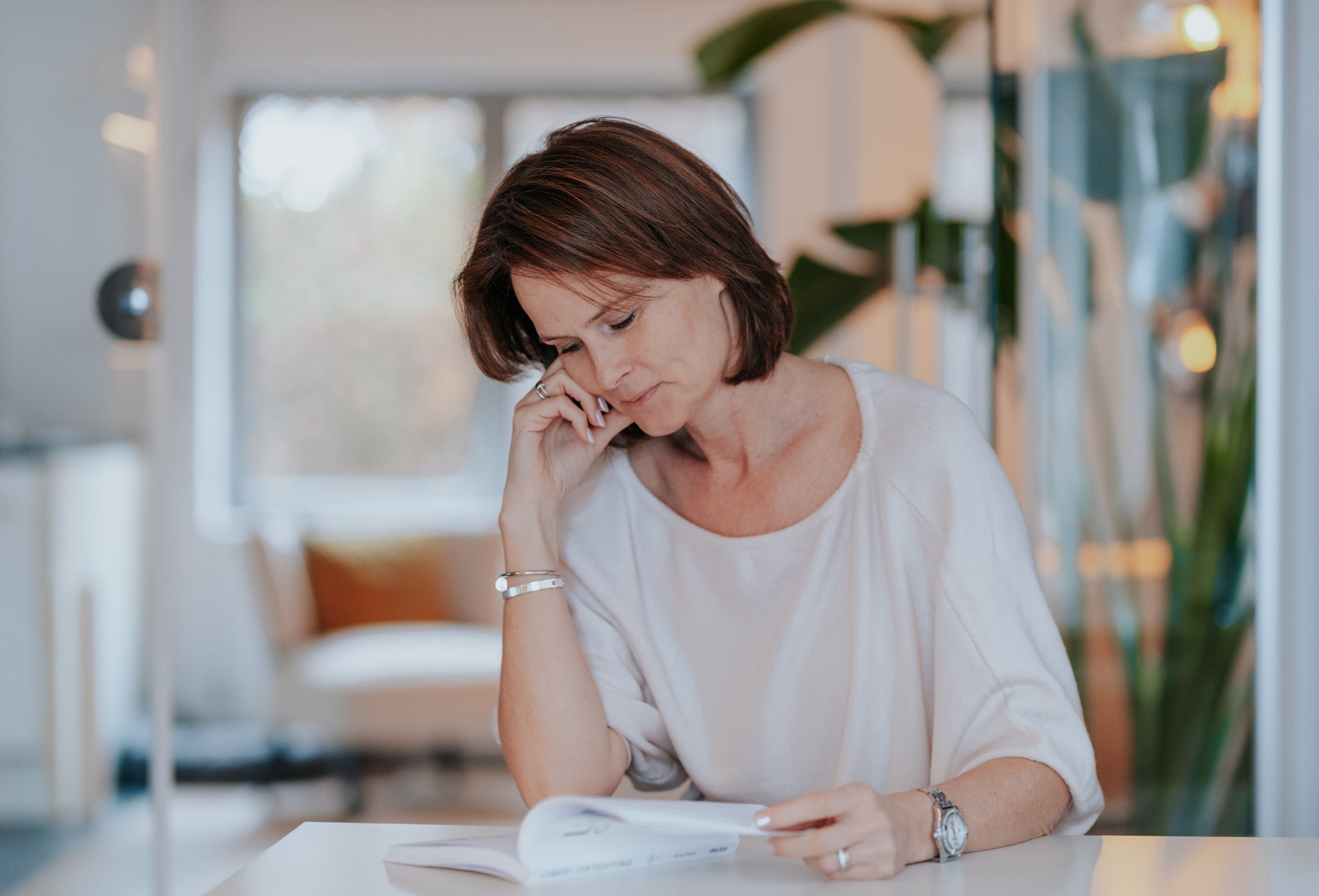 Sofie zit aan buro en leest in een boek, kijkt naar beneden